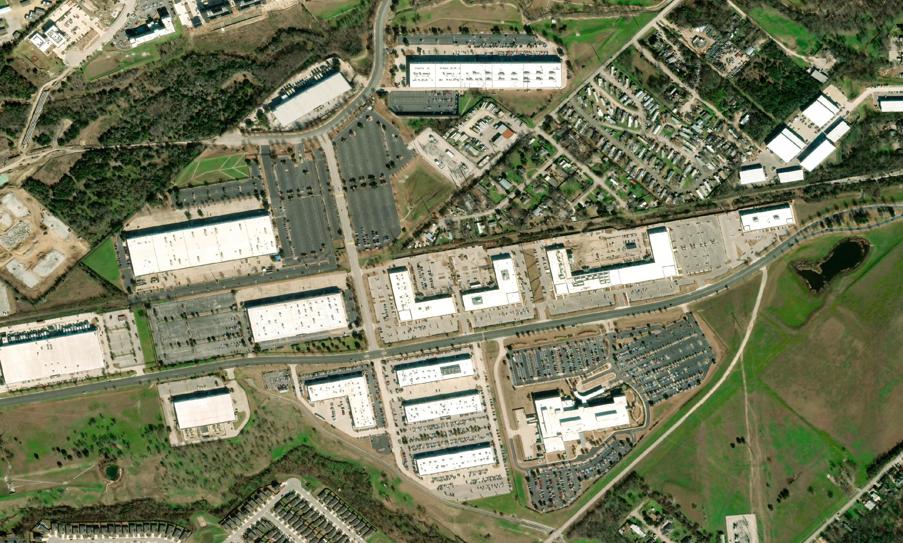Vivid Mosaic satellite basemap of a commercial estate with warehouses, car parks and a rail line beside housing and open grassland