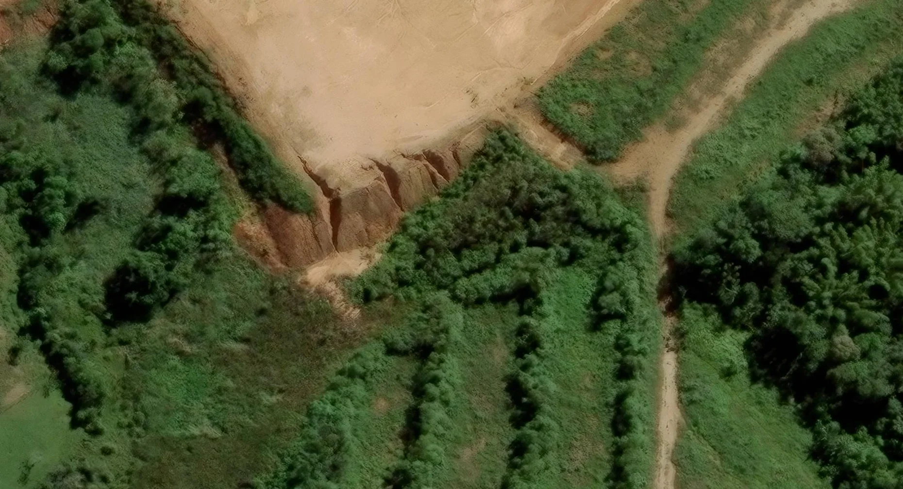 Vivid Mosaic satellite basemap of an eroded scarp beside vegetation and a dirt track