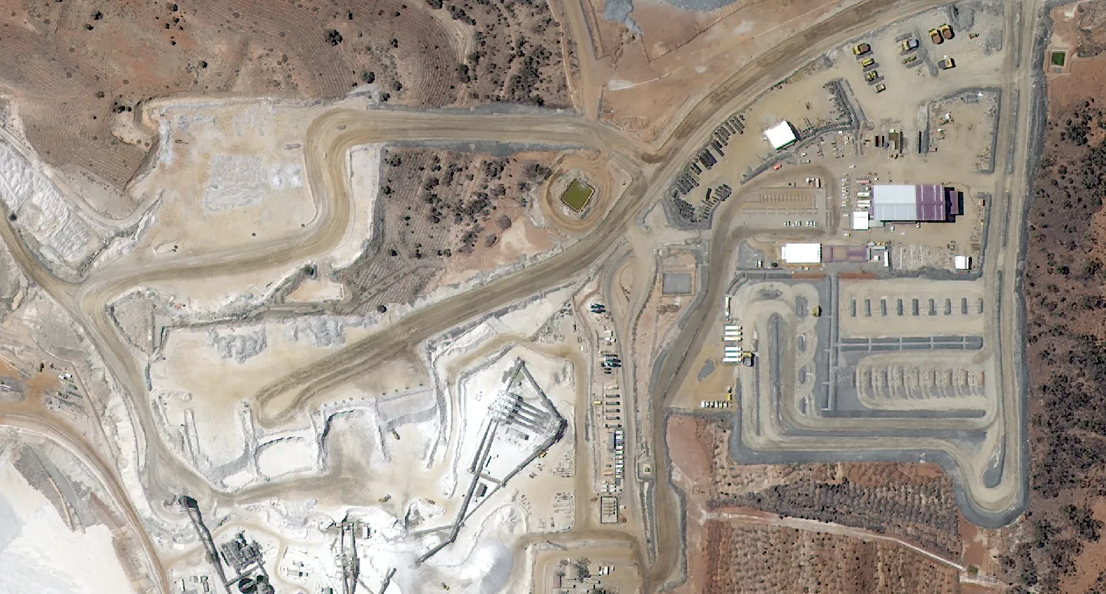 Satellite imagery showing haul trucks and equipment laydown areas at a mine site