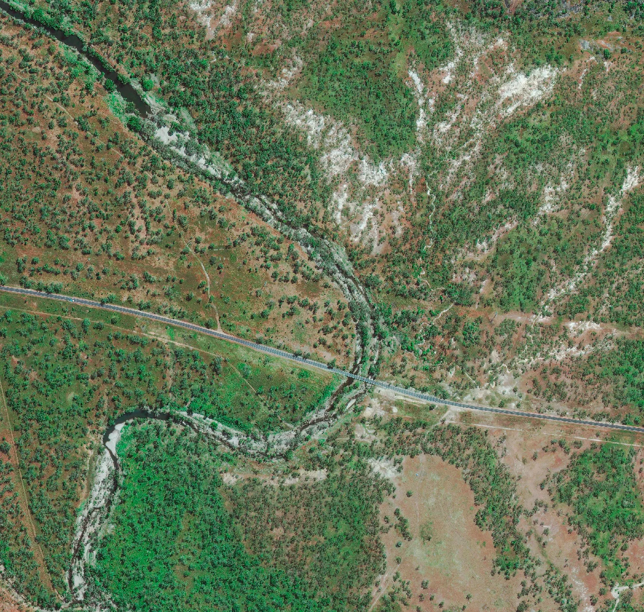 30cm satellite imagery of a sealed road bridging a winding creek through open woodland