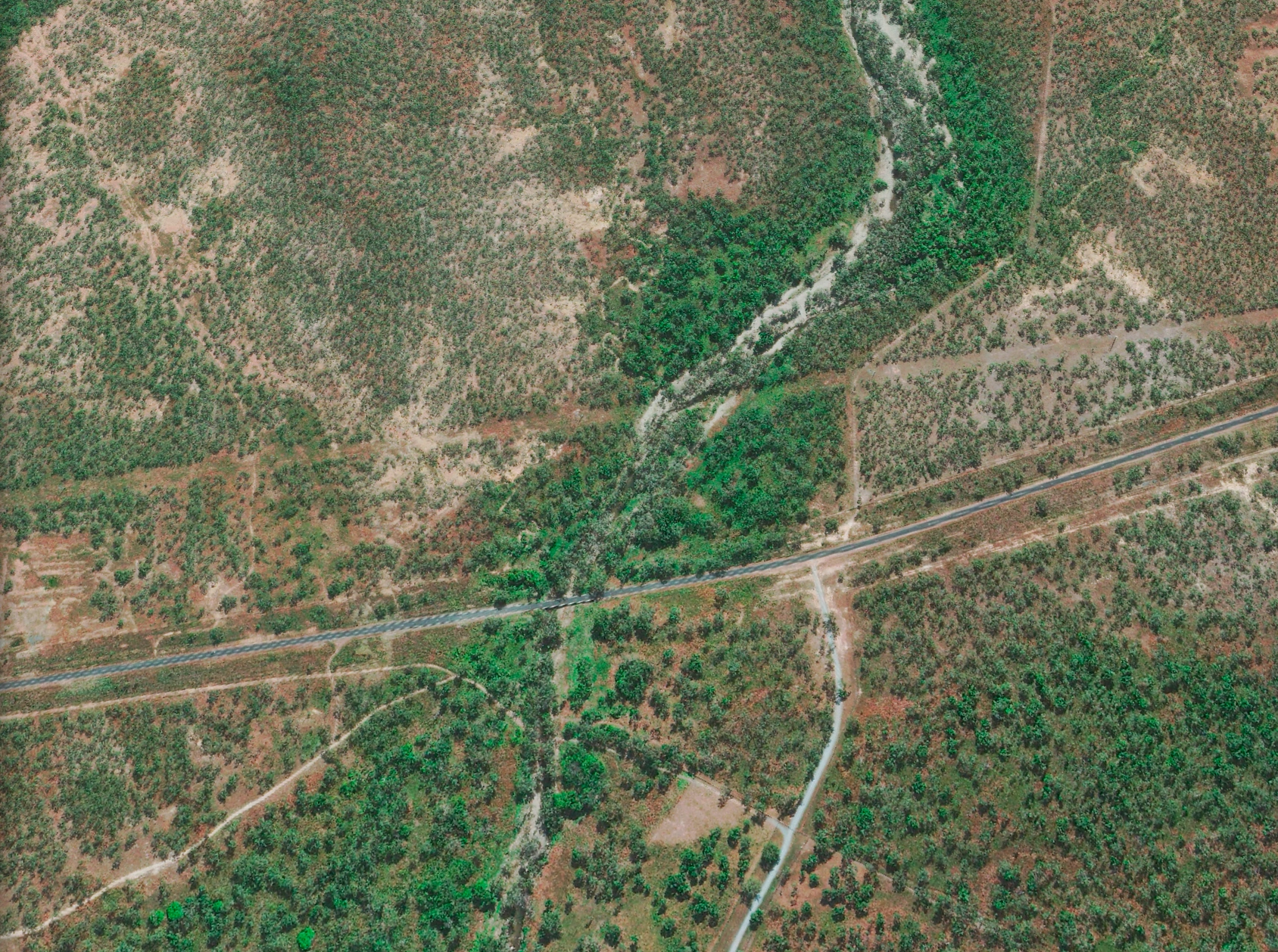 30cm satellite imagery of a sealed road crossing a sandy creek line in open woodland