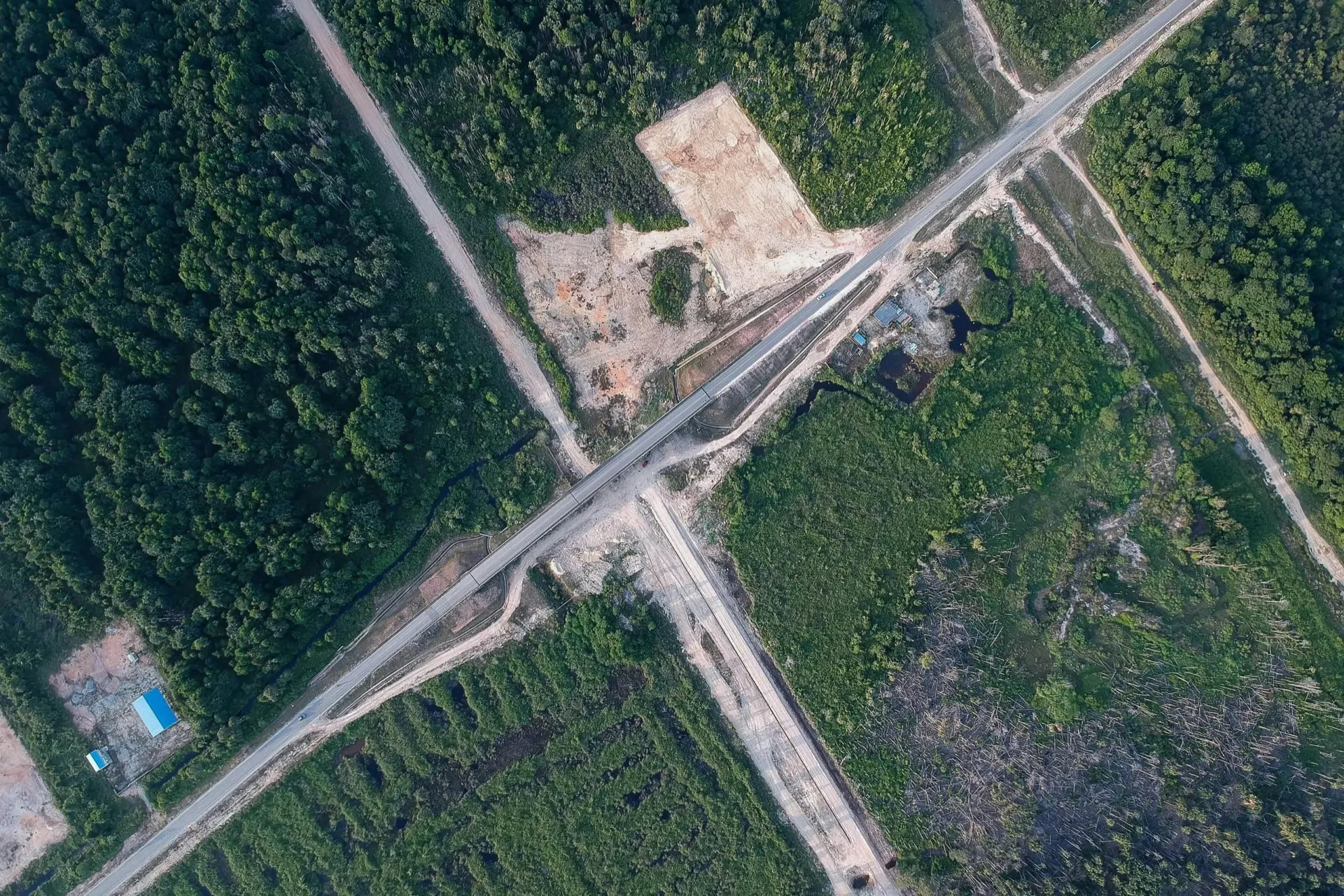 Aerial view of road infrastructure cutting through forest and farmland